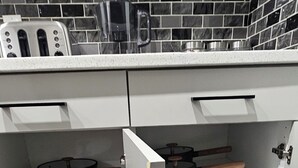Eine Küche mit weißen Schränken, einer schwarz-weißen Fliesenrückwand und einem Holzboden.