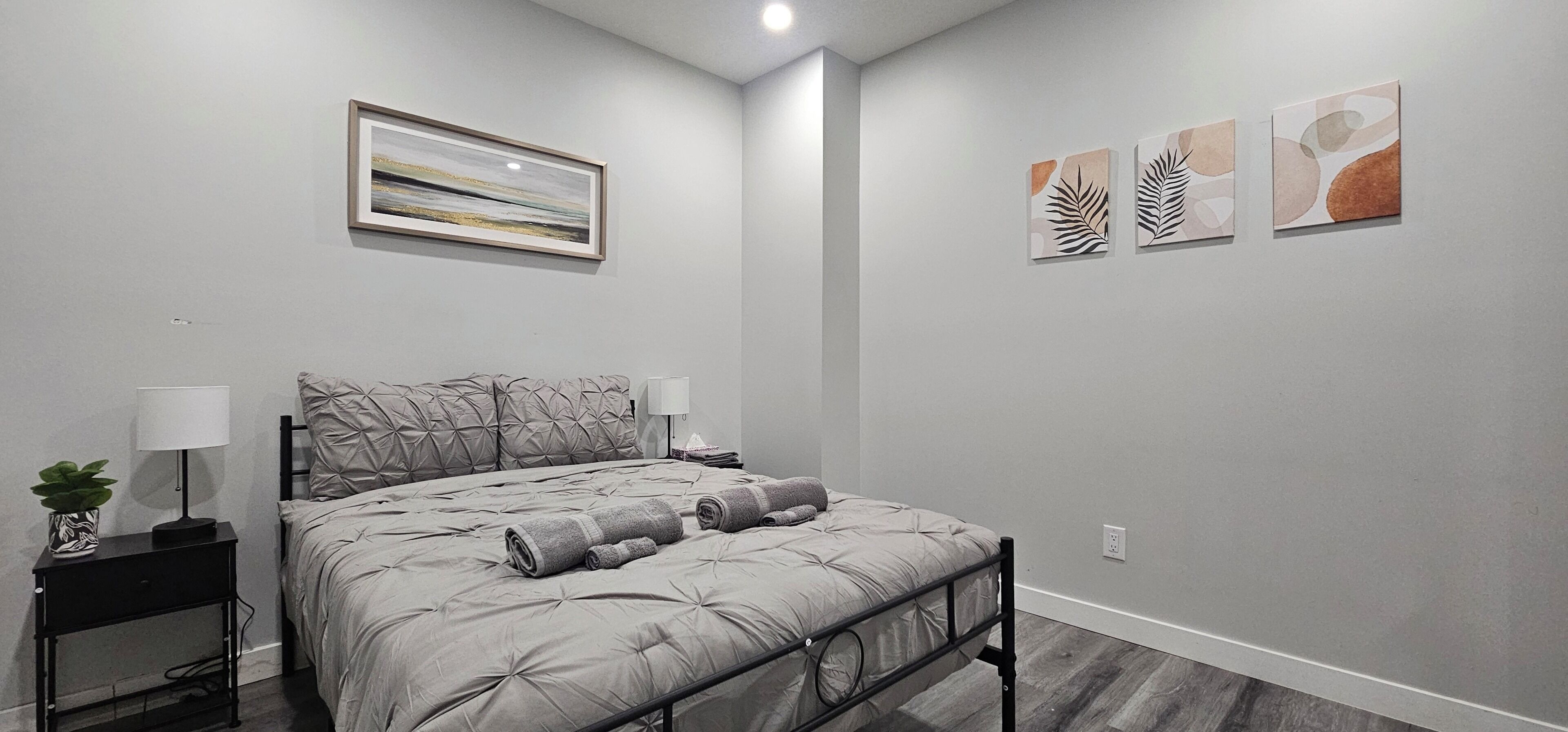 A bedroom with a bed, bedside tables, a lamp, and wall art.