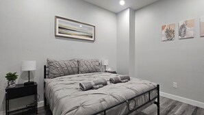 Ein Schlafzimmer mit Bett, Nachttischen, einer Lampe und Wandbildern.