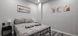 A bedroom with a bed, bedside tables, a lamp, and wall art. - 2 Bedroom NE Calgary Full Basement Suite Boutique Experience (Calgary)
