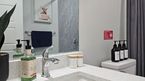 Ein Badezimmer mit Waschbecken, Spiegel und Toilettenartikeln.