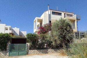 Ein zweistöckiges Wohngebäude mit Balkon, Steinmauer und grünem Tor.