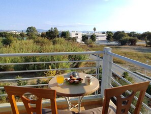 Ein Balkon mit Tisch für zwei Personen, mit Blick auf eine Landschaft aus Gebäuden und Vegetation.