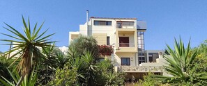 A multi-story building with balconies, surrounded by various plants. - Sofita Di Sofo Kos Vacation Apartment (Kos)