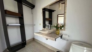 Ein Badezimmer mit Waschbecken, Spiegel, Toilette und Mülleimer.