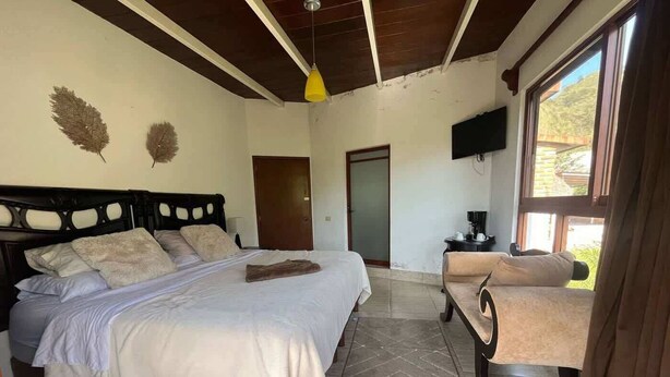 Un dormitorio con cama, una silla, un televisor y una puerta.