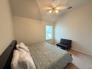 Ein Schlafzimmer mit einem Bett, einer Bank, einem Deckenventilator und einem Fenster.