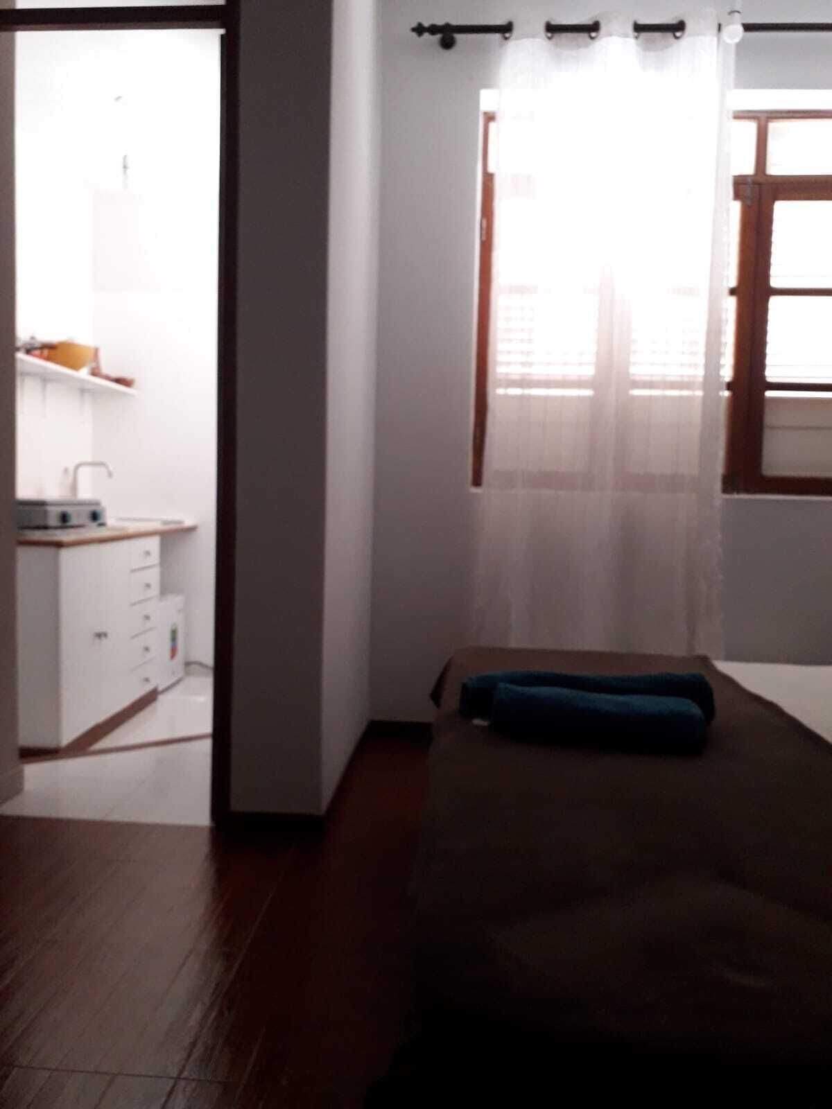Une chambre à coucher avec un lit, une fenêtre avec des rideaux et une vue sur une salle de bain.