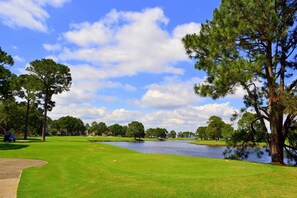 A golf course with a pond, trees, and a clear sky. - Beachside 2 4370 Coastal Living decor direct beach access pool (Miramar Beach)