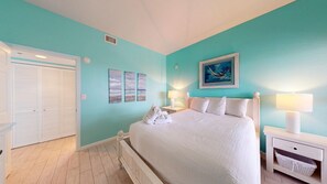 A bedroom with a bed, a nightstand, a lamp, a painting, and a closet. - Beachside 2 4370 Coastal Living decor direct beach access pool (Miramar Beach)