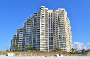 Un hotel moderno de gran altura con múltiples balcones, techo plano y ubicación frente a la playa.