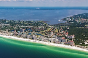 An aerial view of a coastal resort with multiple high-rise hotels, a beachfront, and surrounding greenery. - Beachside 2 4370 Coastal Living decor direct beach access pool (Miramar Beach)