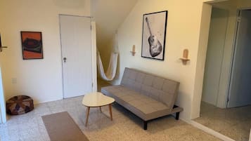 A room with a sofa, a small table, a hanging chair, and a door.