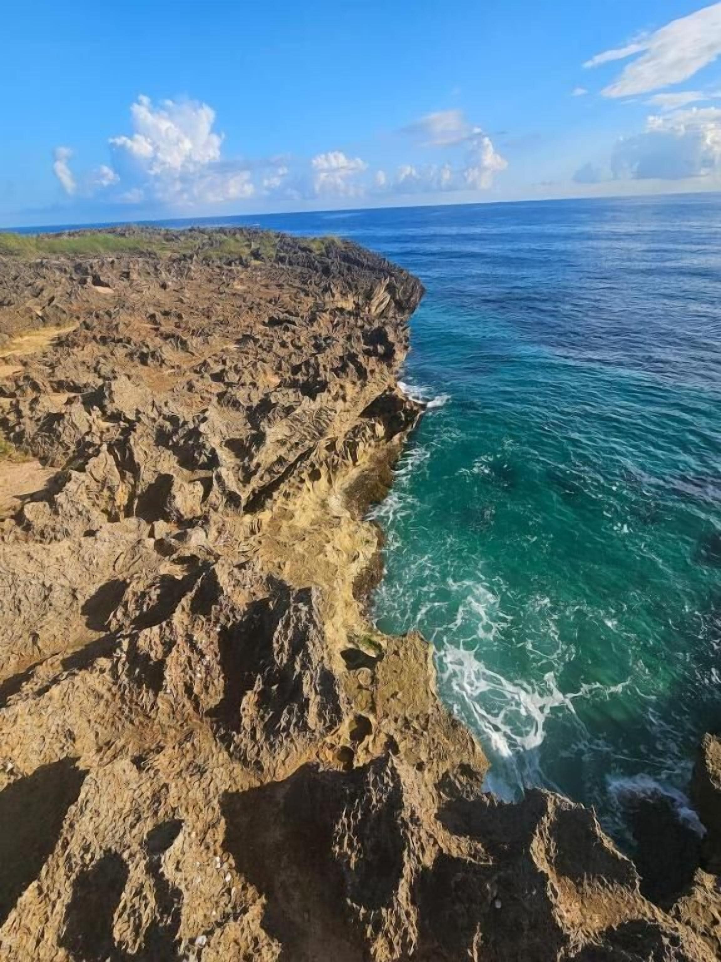 A coastal landscape with rocky terrain and clear blue waters.