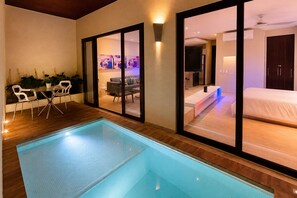 A modern hotel room with a glass-enclosed pool, a dining area with chairs, and a bedroom with a bed. - Luxury Loft Parque de Novios-ByHuespedia (Santa Marta)