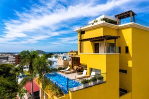 A yellow building with a rooftop pool and lounge chairs. - Luxury Loft Parque de Novios-ByHuespedia (Santa Marta)