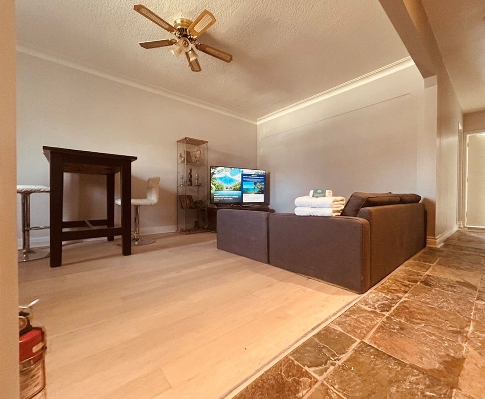Una sala de estar con sofá, televisor y ventilador de techo.