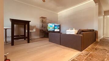 Una sala de estar con sofá, televisor y ventilador de techo.
