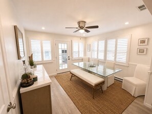 A modern kitchen with a glass dining table, white cabinetry, and a ceiling fan. - Perfect 2-bedroom cottage in the Village Green Community of enchanting Cape May (Cape May)