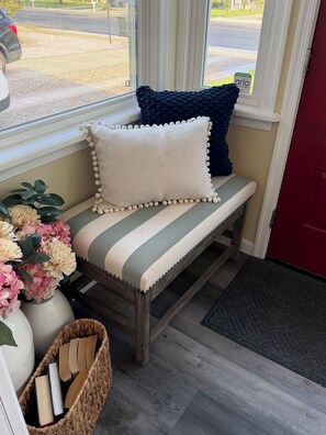 A bench with striped cushions and decorative pillows, a basket of books, and a vase of flowers. - Perfect 2-bedroom cottage in the Village Green Community of enchanting Cape May (Cape May)