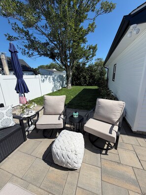 Un patio con mobili da esterno, un tavolino e un oggetto decorativo.