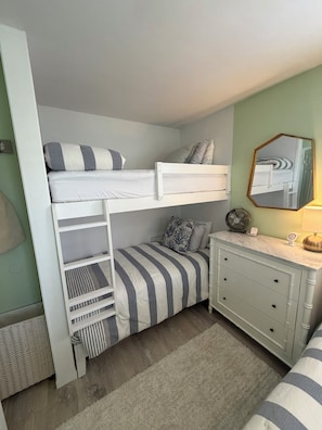 A bunk bed with a lower bunk, a dresser with drawers, a mirror, and a fan on the floor. - Perfect 2-bedroom cottage in the Village Green Community of enchanting Cape May (Cape May)