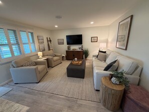 A living room with a sofa, a coffee table, a TV, and a lamp. - Perfect 2-bedroom cottage in the Village Green Community of enchanting Cape May (Cape May)