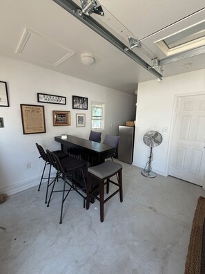 A dining area with a table and chairs, a standing fan, and framed pictures on the wall. - Perfect 2-bedroom cottage in the Village Green Community of enchanting Cape May (Cape May)