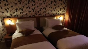 Une chambre d’hôtel avec deux lits, chacun doté d’une tête de lit, de tables de chevet et de lampes.
