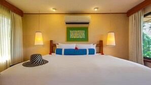 Una camera d'albergo con un letto grande, due lampade ai comodini, un condizionatore e una finestra con tende.