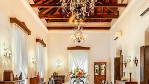 A dining room with a large wooden table, ornate chairs, a chandelier, and patterned flooring. - Ama Stays And Trails Cardozo House (Candolim)
