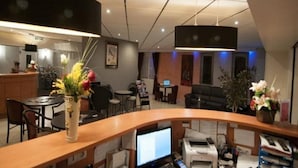 A reception area with a curved desk, computers, printers, and a variety of seating options including chairs and a sofa. - Comfort Hotel Emerainville Marne-la-vallee (Emerainville)