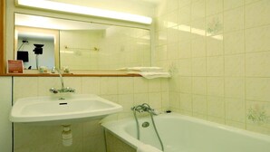 A bathroom with a sink, mirror, and bathtub. - Comfort Hotel Emerainville Marne-la-vallee (Emerainville)