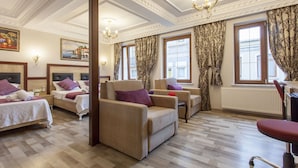 Hotellihuone, jossa on kaksi sänkyä, sohva, tuoli ja ikkuna, jossa on verhot.