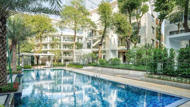 A swimming pool surrounded by greenery and modern buildings.