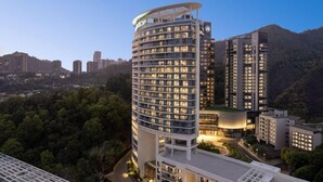 A modern hotel with multiple floors, a distinctive curved corner design, and a well-lit facade.