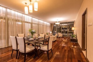 A spacious dining area with a wooden table set for six, surrounded by white upholstered chairs. - Fraser Place Shekou (Shenzhen)