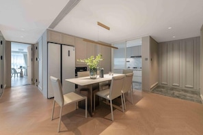 A modern kitchen with a dining area, featuring a central island, pendant lighting, and a view into the adjacent dining room.