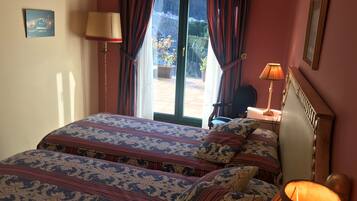 Una habitación de hotel con cama, dos lámparas, una silla y vistas al exterior.