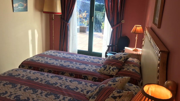 Una habitación de hotel con cama, dos lámparas, una silla y vistas al exterior.