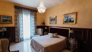 Habitación de hotel con una cama grande, una silla, un escritorio, una lámpara y una araña.
