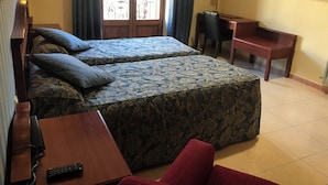 Habitación de hotel con dos camas, un escritorio, una silla, un televisor y un teléfono.