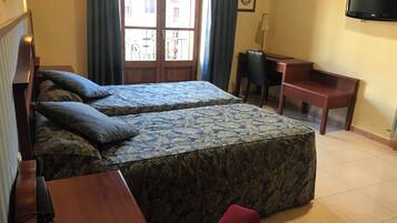 Habitación de hotel con dos camas, un escritorio, una silla, un televisor y un teléfono.
