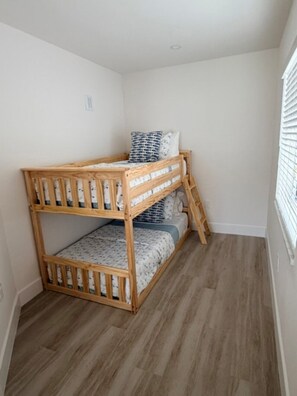 Ein Stockbett in einem Zimmer mit Holzboden und weißen Wänden.