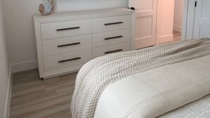 A bedroom with a bed, a dresser, a television, and a door leading to another room. - 18 On the Bay Suite #6 (Indian Rocks Beach)