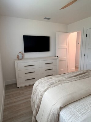 A bedroom with a bed, a dresser, a television, and a door leading to another room. - 18 On the Bay Suite #6 (Indian Rocks Beach)