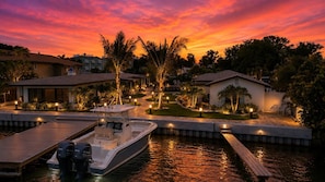 A waterfront property with a dock, a boat, and houses with outdoor lighting. - 18 On the Bay Suite #5 (Indian Rocks Beach)
