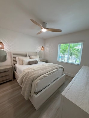 A bedroom with a bed, bedside tables, a ceiling fan, a window with a view, and a desk. - 18 On the Bay Suite #2 (Indian Rocks Beach)