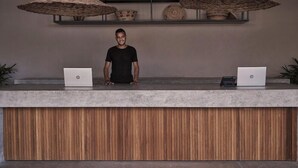 A reception desk with two laptops, a person standing behind it, and two woven lamps above. - Casa Cook El Gouna (El Gouna)