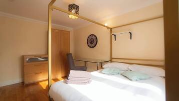 A bedroom with a bed, a chair, a wardrobe, a clock, and a hanging light fixture.